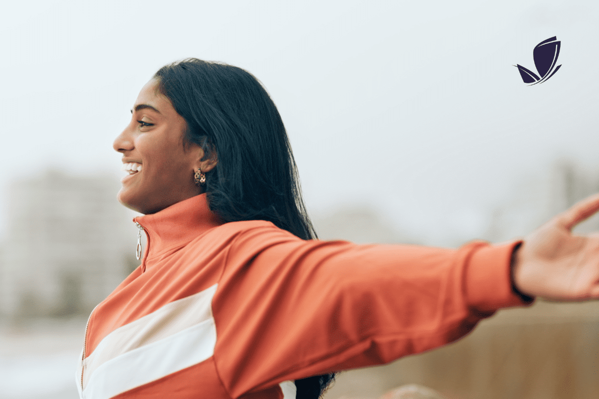 indian woman smiling with arms spread wide. LightRx logo in top right corner.